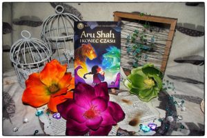 Stojący egzemplarz powieści Aru Shah i koniec czasu w otoczeniu kwiatów i dwóch ozdobnych klatek